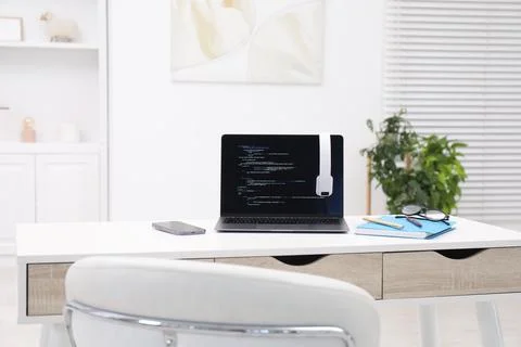 Programmer's workplace. Modern laptop with unfinished code, headphones and .. 库存照片