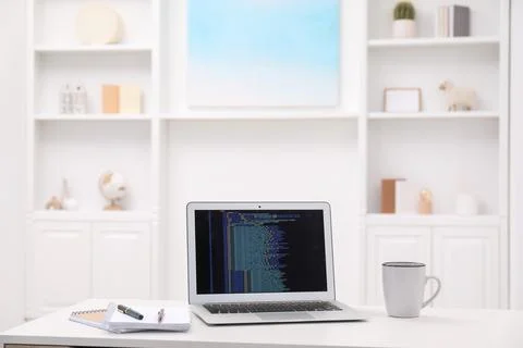 Programmer's workplace. Modern laptop with unfinished code, cup and station.. Stock Photos