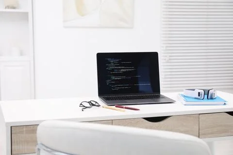 Programmer's workplace. Modern laptop with unfinished code, headphones and .. 库存照片