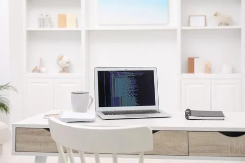 Programmer's workplace. Modern laptop with unfinished code, cup and noteboo.. 库存照片