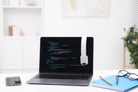Programmer's workplace. Modern laptop with unfinished code, headphones and .. Stock Photos