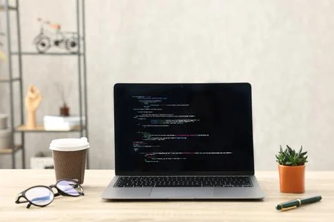 Programmer's workplace. Modern laptop with unfinished code, paper cup of dr.. Stock Photos