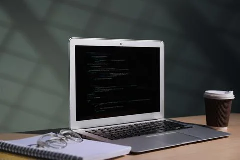 Programmer's workplace. Modern laptop with unfinished code, notebooks, glas.. 写真素材
