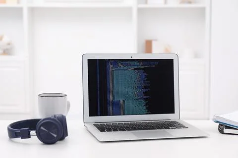 Programmer's workplace. Modern laptop with unfinished code, headphones and .. 写真素材