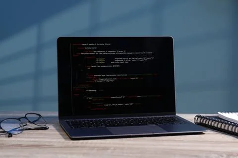 Programmer's workplace. Modern laptop with unfinished code, glasses and not.. Stock Photos