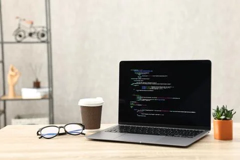 Programmer's workplace. Modern laptop with unfinished code, paper cup of dr.. 스톡 사진