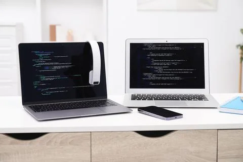 Programmer's workplace. Modern laptops with unfinished code, headphones and.. Stock Photos