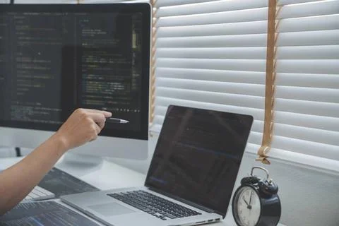 Programmierer, der Programmcode mit zwei Monitoren schreibt und als Hacker... Stock-Fotos