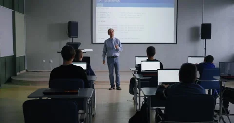 Programming Classes, Middle-Aged Professor Of Computer Science Teaching Young Stock Footage 280640971