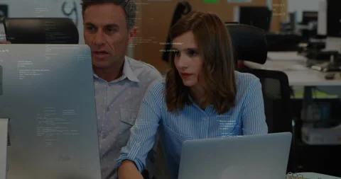 Programming code animation over two colleagues working on computers in office Stock Footage 303739868
