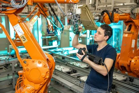 Programming of robot arms for a new product by a production engineer Stock Photos