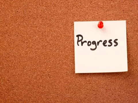 Progress note pinned to brown corkboard with red pushpin Stock Photos