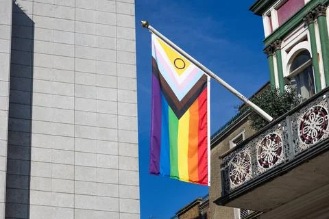 Progress pride flag hanging from a city building Stock Photos