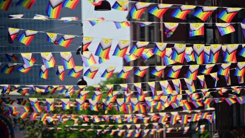 Progress pride flags hanging across a city street symbolizing community Stock Footage 325223977