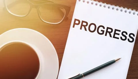 PROGRESS text on paper with cup of coffee and glasses on wooden background .. Stock Photos