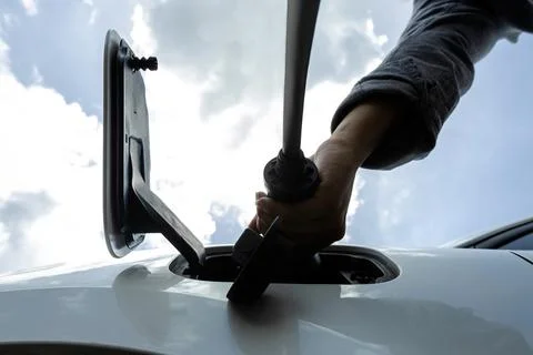 Progressive below view image of hand insert EV charger to socket with cloudscape 스톡 사진