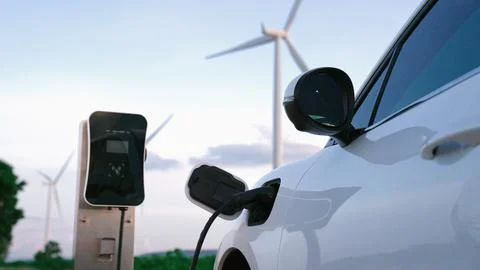 Progressive combination of EV car, charging station and wind turbine. Stock Photos