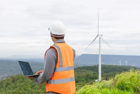 Progressive concept of engineer working in the wind farm atop of the mountain. Stock Photos