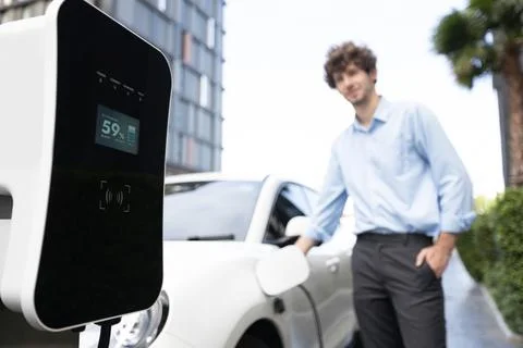 Progressive concept of focus EV car at charging station with blur man background Foto stock