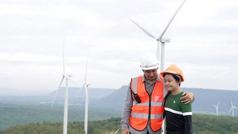 Progressive engineer with his son in the wind farm atop of the mountain. Stock Photos