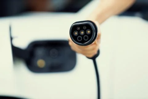 Progressive idea of focus hand pointing charging plug at camera, blur background Stock Photos