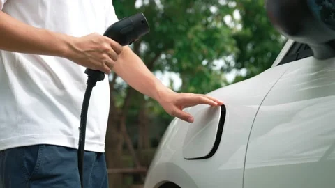 Progressive man install cable plug to his EV car from home charging station. Stock-Footage 221112795