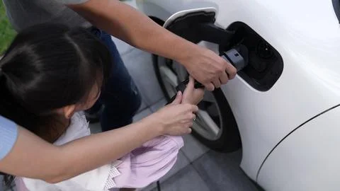 Progressive parent have returned from picking up daughter at school with EV car. Stock Photos