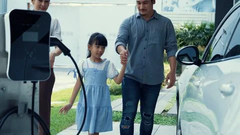 Progressive parent have returned from picking up daughter at school with EV car. Stock Photos