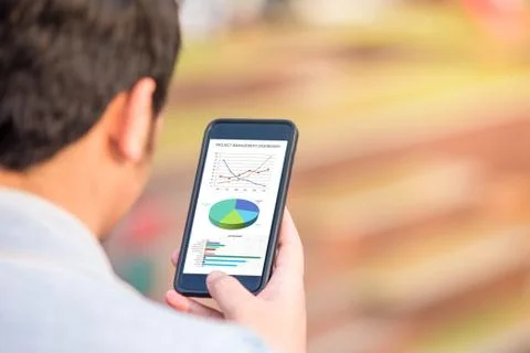 Project management dashboard concept. Man holding phone with excel project dashb Stock Photos