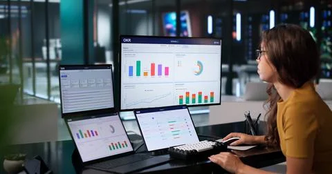 Project Manager Analyzes Dual Touchscreen Laptop To Track OKR Progress Carefu Stock Photos