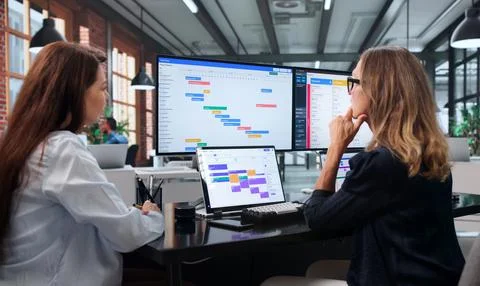 Project Manager And Assistant Focus On Updating Busy Project Timeline Togethe Stock Photos