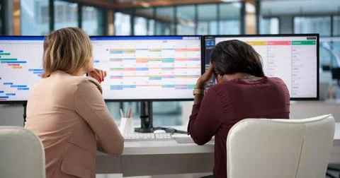 Project Manager And Assistant Review Long, Boring Project Schedule On Compute Stock Photos