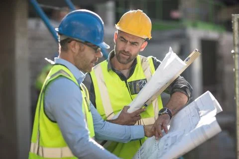 Project manager and construction worker looking at plans Stock Photos