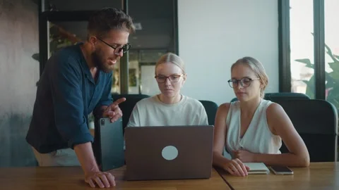 Project manager giving thumbs up while mentoring two female colleagues engaged Stock Footage 312114001