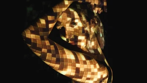 Projected disco ball pattern on face and arms of attractive, young woman. Stock Footage 77402238