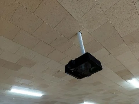 A projector hanging from the ceiling of a building Stock Photos