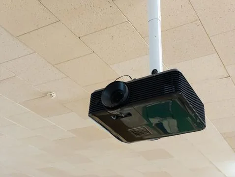 A projector hanging from the ceiling in a room Stock Photos