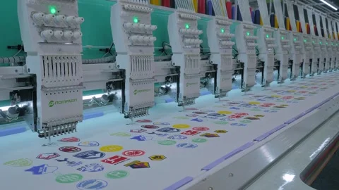 Promaker embroidery machine is creating decorative sports logos on the fabric Stock Footage 329943390