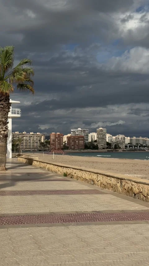 Promenade along the beach under dramatic cloudy skies in San Juan Playa, Spain Stock Footage 294821327