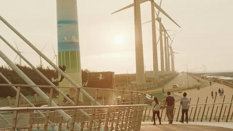 Promenade on the background of rotating windmills and golden sunset. Taiwan Stock Footage 124334892