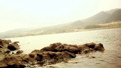 Prominently in the foreground are dark, rugged rocks partially submerged Stock Footage 320408644