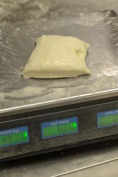Proofed bread dough resting on floured metal tray in bakery on digital scale Stock Photos