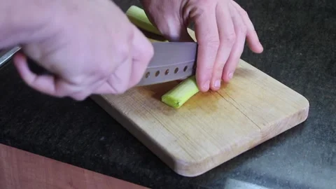 Proper knife techniques for slicing vegetables in a home kitchen setting Stock Footage 294623080