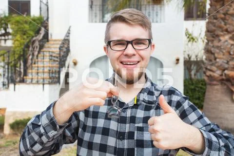 Property, ownership, new home and people concept - young man with keys standing Stock Photos