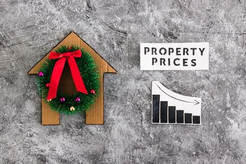 Property prices text and graph with stats going down next to cardboard hous.. Foto stock