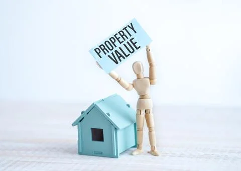 Property Value text on paper in the hands of a wooden man and wooden home. Stock Photos
