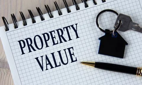 PROPERTY VALUE - words in a white notebook with a pen and a house keychain wi Stock Photos