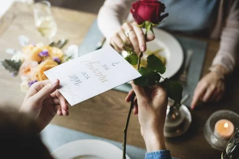 Proposing with a red rose at the dinner table Stock Photos