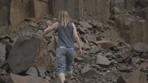 ProRes 4:2:2 log, slow motion footage. Young woman walking in basalt career. Stock Footage 109347032