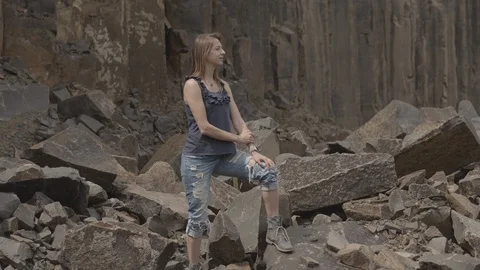 ProRes 4:2:2 log, slow motion footage. Young woman walking in basalt career. Stock Footage 109349254